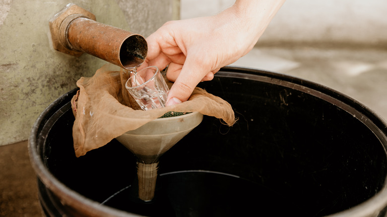 Person collecting moonshine from tap.