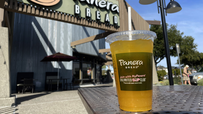 A yellow Panera Bread drink outdoors on a table