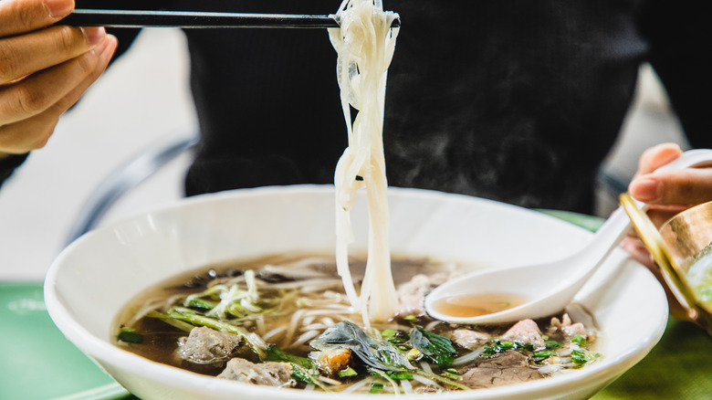 Person eating a bowl of pho