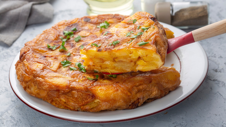 Spanish omelette with rubber spatula removing a slice