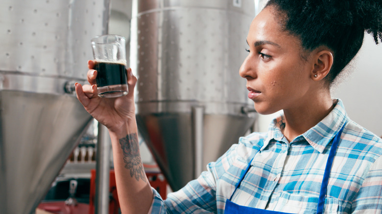 Craft brewer holding glass of dark beer