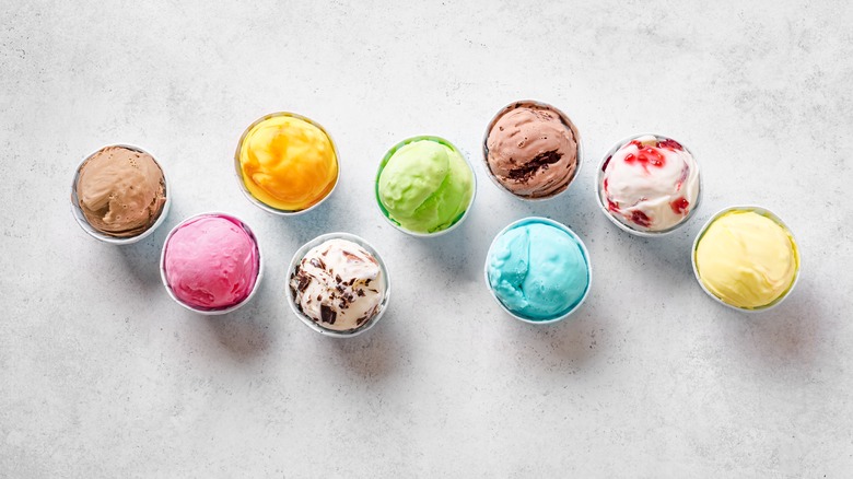 Nine cups of various frozen yogurts on a table