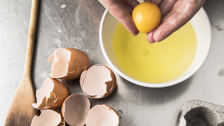 Closeup of hands separating an egg yolk