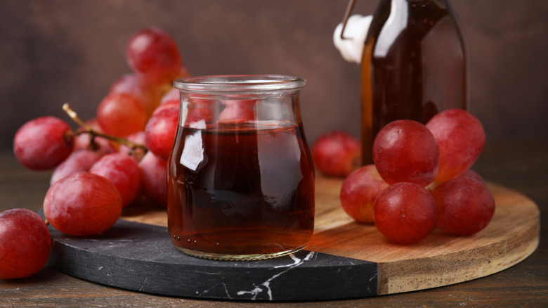 Red wine vinegar in a pitcher surrounded by grapes