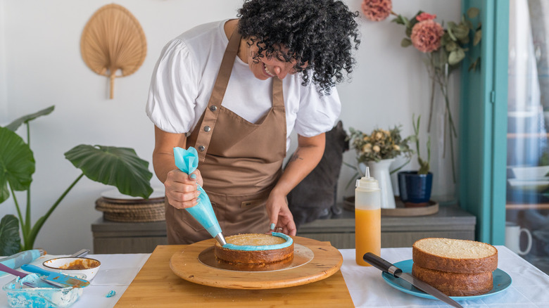 A woman piping frosting on a cake