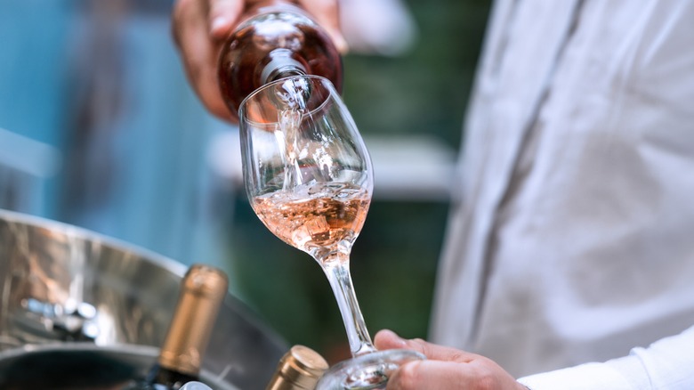 Person pouring blush wine