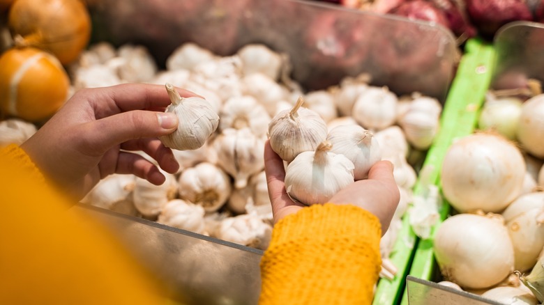 Hands holding garlic bulbs at a store