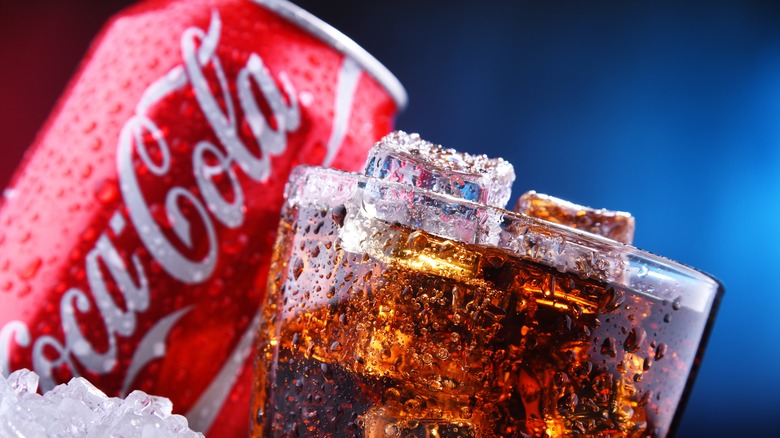 A glass of Coke in front of a Coke can