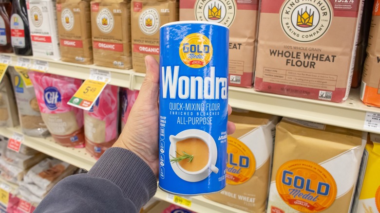 Person holding container of Wondra flour at grocery store