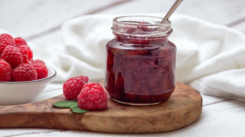 Jar of raspberry jam with fresh raspberries