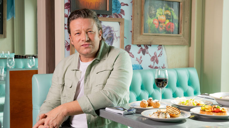 Jamie Oliver sitting at a restaurant table
