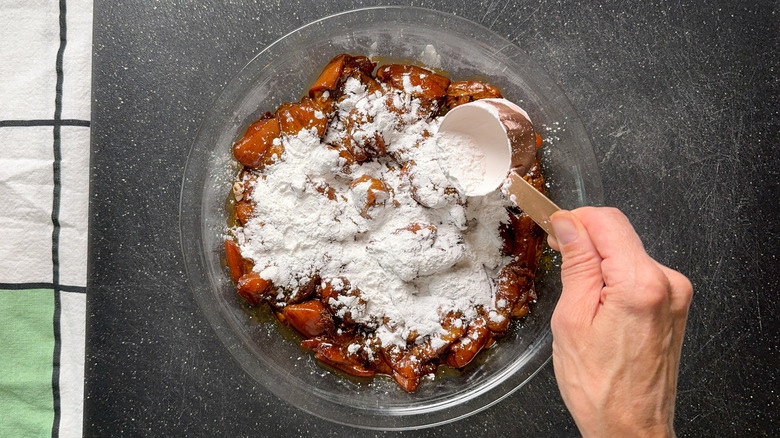 Dredging marinated chicken thighs with potato starch in pie plate