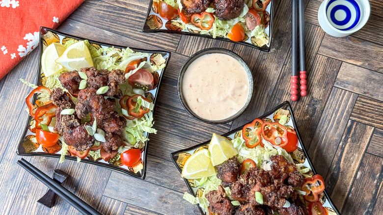 Japanese twice-fried chicken karaage on plates with garnishes and dipping sauce