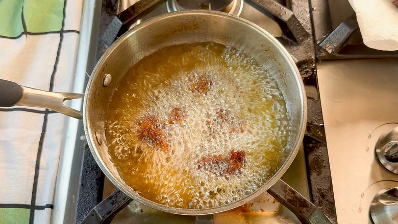 Chicken karaage frying in hot oil in pot on stovetop