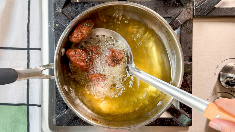 Removing chicken karaage from hot oil with slotted spoon