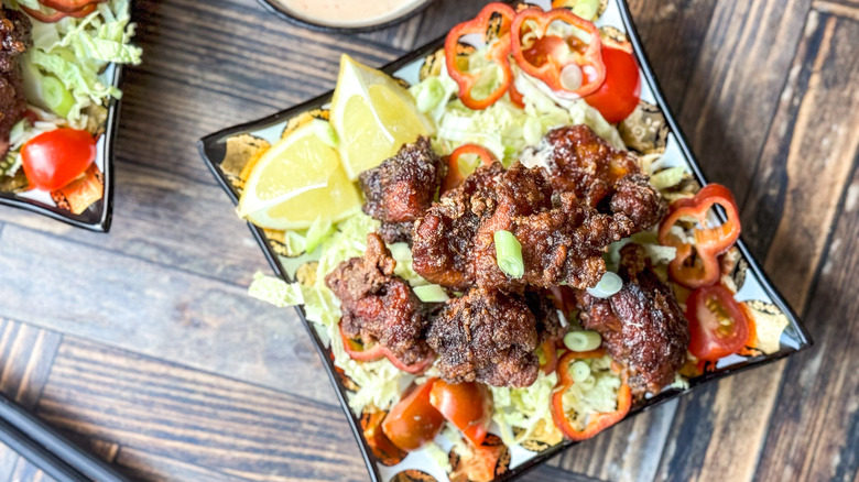 Chicken karaage served over shredded cabbage, peppers, and tomatoes with lemon wedges