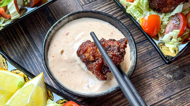 Dipping chicken karaage in spicy mayo sauce with chopsticks