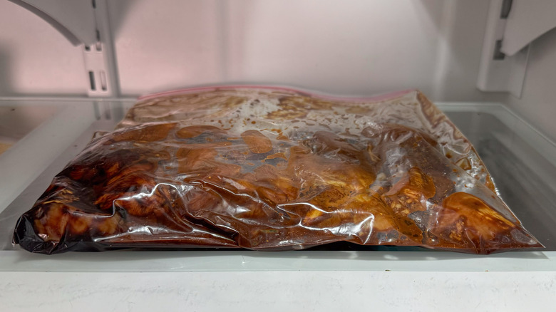 Boneless skinless chicken thigh pieces marinating in ziplock bag in refrigerator