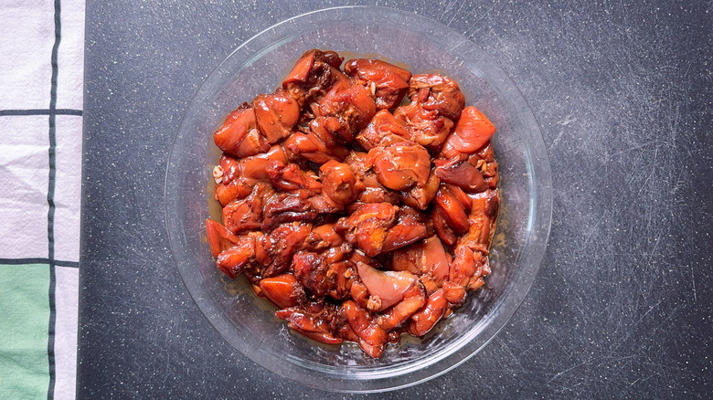 Marinated boneless skinless chicken thigh pieces in pie plate on cutting board