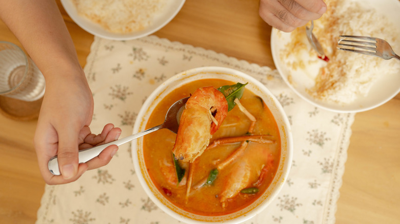 A hand spooning curry out of a food container.
