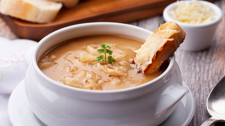 image of french onion soup with a small piece of bread in a white bowl