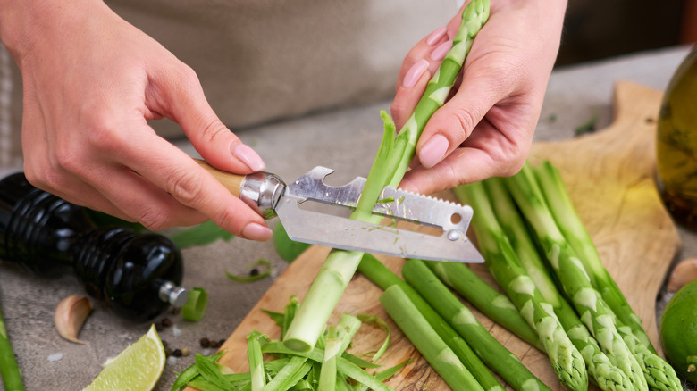 Person peeling stalks of asparagus