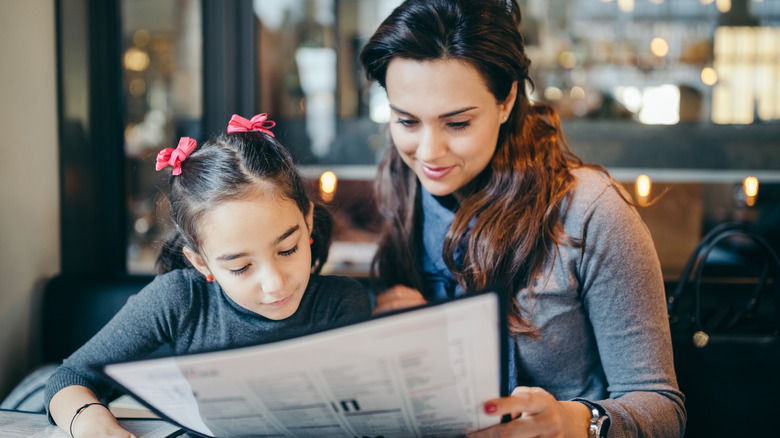 mom and daughter reading menu