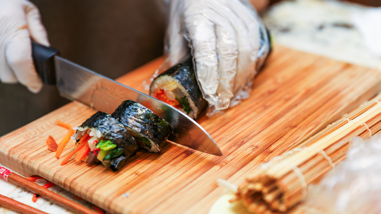 Hands slice a kimbap roll