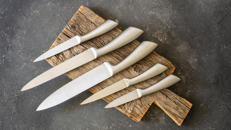 Various knives on wood board against slate background