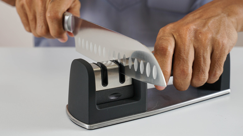 Man using a pull-through knife sharpener