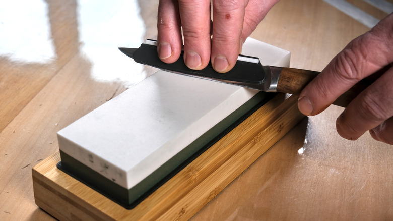 Close-up of a person using a whetsone to sharpen a knife