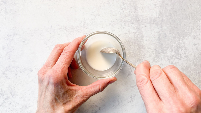Mixing cornstarch and water in small glass bowl with spoon