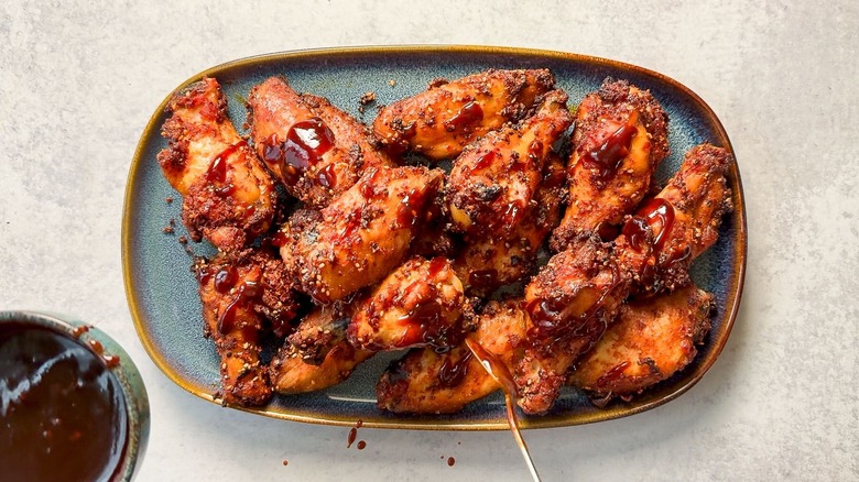 Korean dry-rubbed wings on serving platter drizzled with dipping sauce