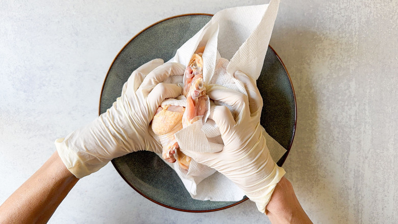 Drying chicken wings with paper towels and latex gloves