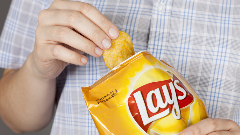 Person eating Lay's potato chips from bag