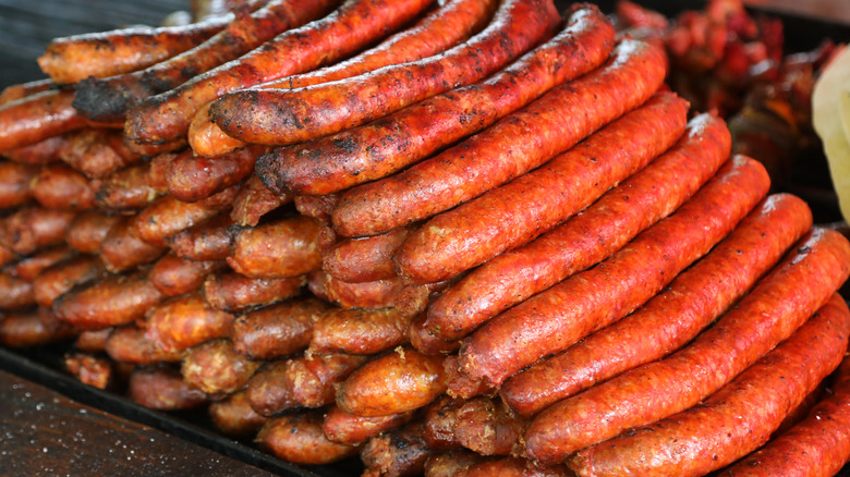 Cooked hot dogs stacked on a grill