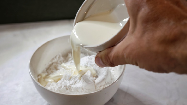 pouring cream into bowl of powdered sugar