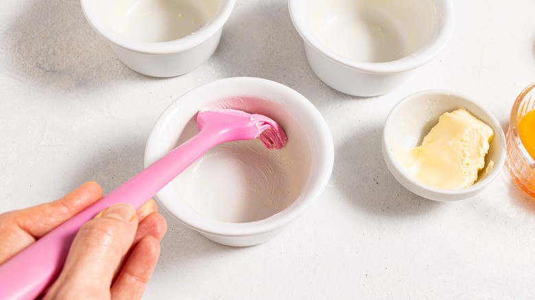 Greasing a ramekin with butter using pink silicon spatula