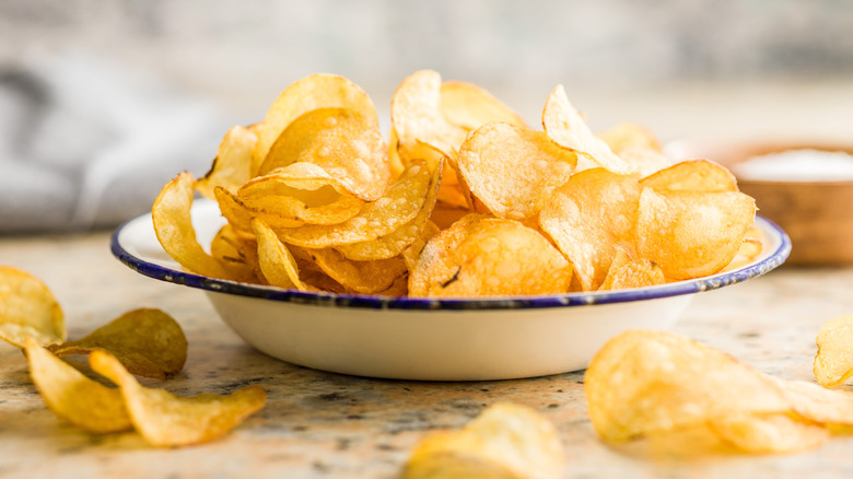 Crispy potato chips in a bowl on a kitchen counter.