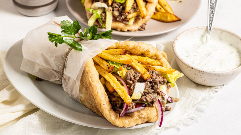 Ground beef gyros on a plate with a side of tzatziki