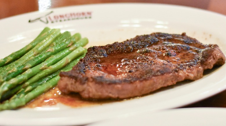 A steak with asparagus on a white plate