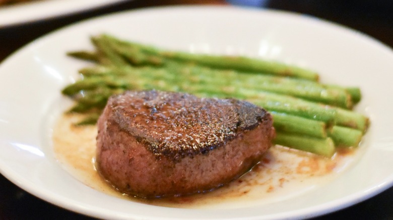 A steak with asparagus on a white plate