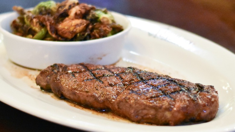 A steak with brussel sprouts on a white plate