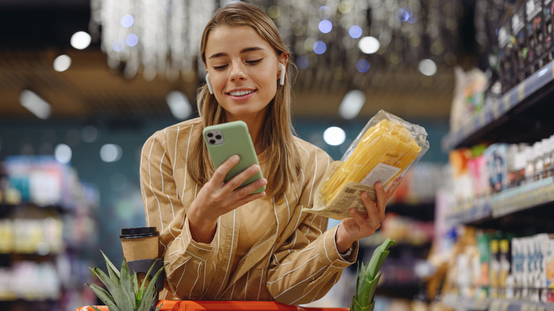 Woman looking at her phone while grocery shopping