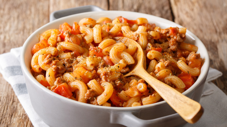 Macaroni and tomato goulash with ground beef in a white casserole dish