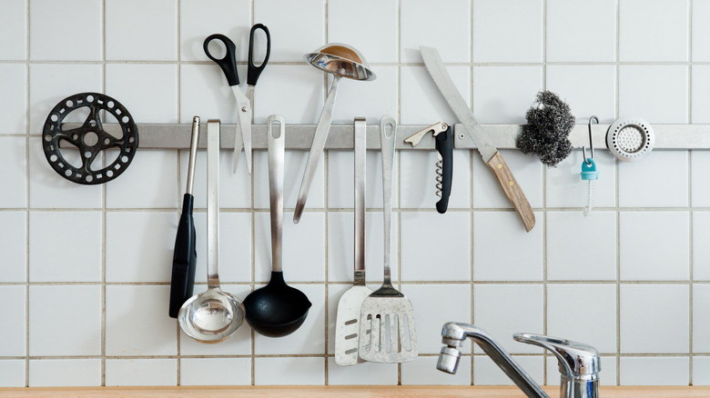 Magnetic knife strip holding assorted kitchen tools and utensils