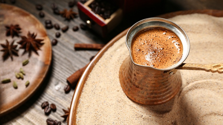 Turkish coffee brewing with spices in background