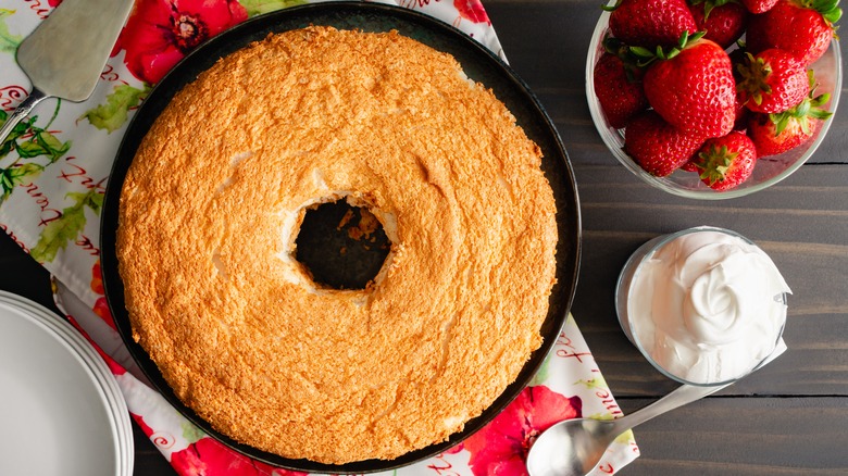 Angel food cake next to strawberries and whipped cream