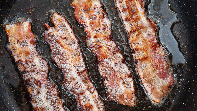 Bacon strips frying in a skillet