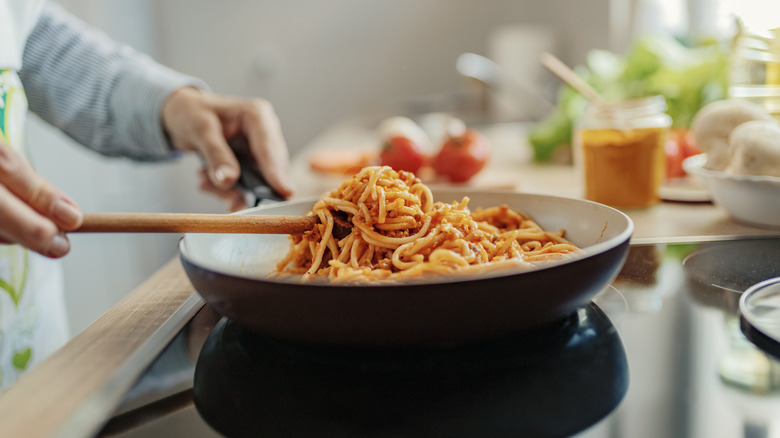 woman cooking pasta in a pan on stove
